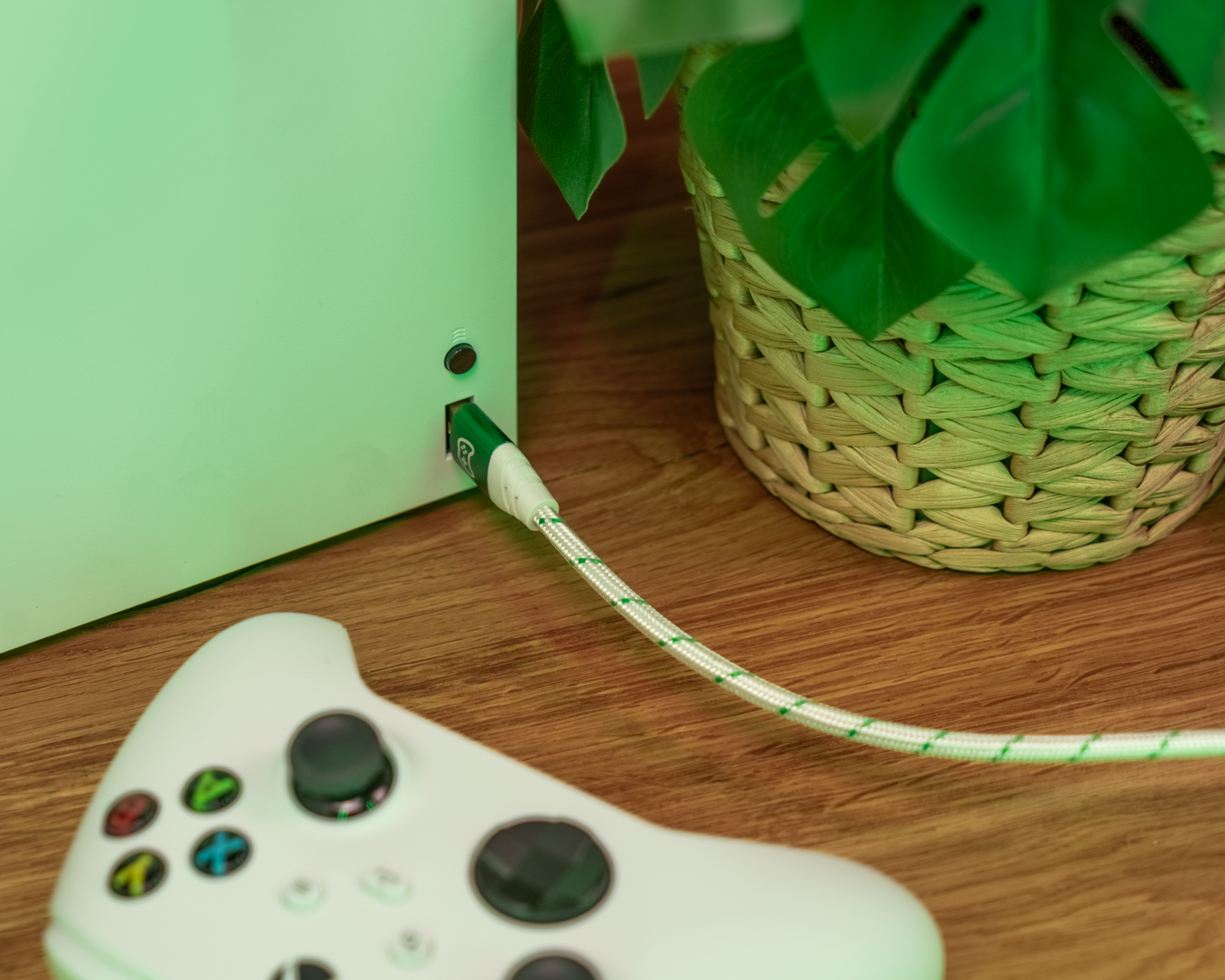 Konsole links mit grünem Kabel, Controller unscharf im Vordergrund